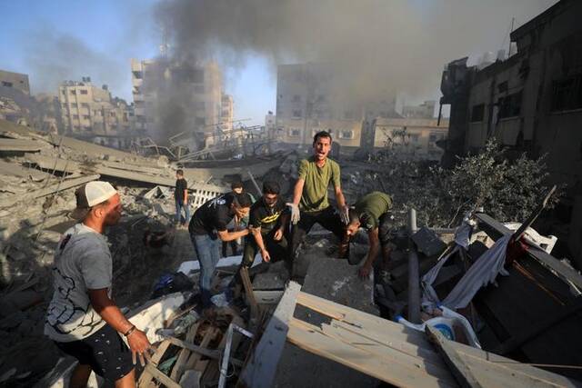 10月25日，在加沙城，人们在建筑废墟中搜寻伤者。新华社发（亚西尔·库迪摄）