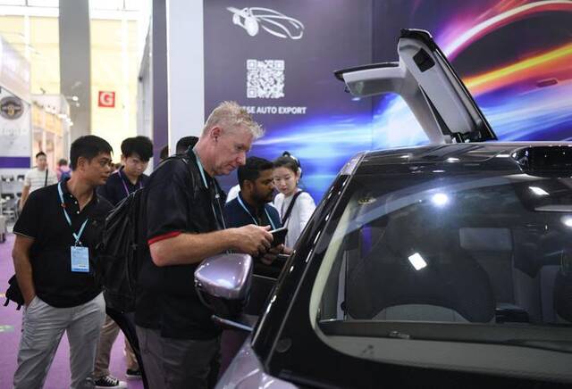 2023年10月16日，外国采购商观看广交会中国新能源汽车展台。