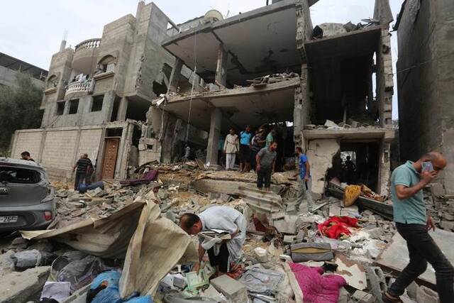 10月29日，在加沙地带南部城市拉法，人们查看被以军空袭损毁的建筑。新华社发（哈立德·奥马尔摄）