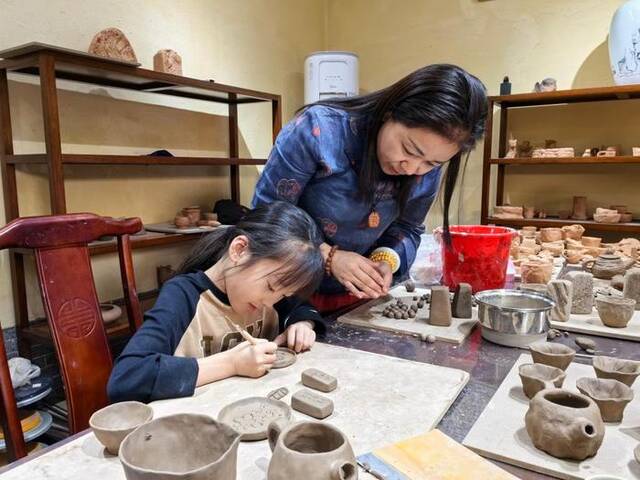 张金霞在教小朋友制作澄泥摆件。新华社记者袁敏摄