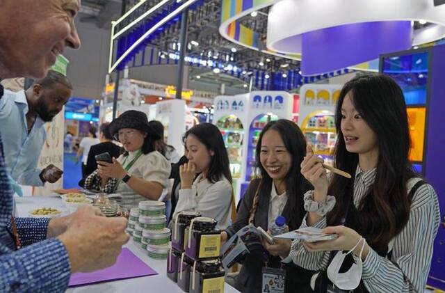 11月5日，在第六届进博会食品及农产品展区，参观者试吃贝宁蜂蜜。新华社记者刘颖摄