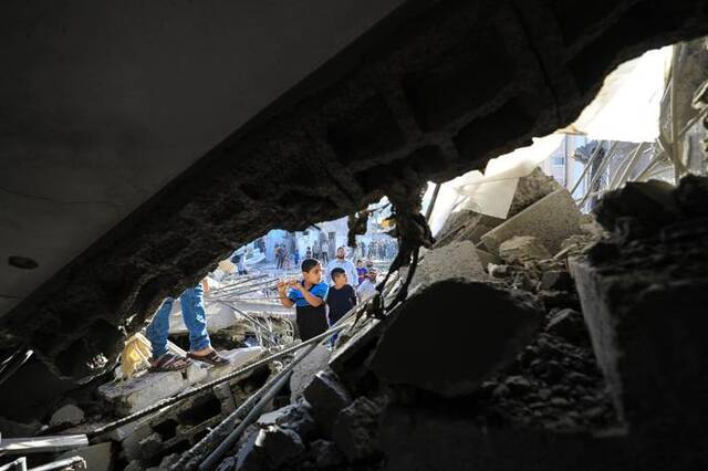 11月4日，在加沙地带南部城市汗尤尼斯，人们在遭以色列袭击后的建筑废墟中实施救援。新华社发（亚西尔·库迪摄）