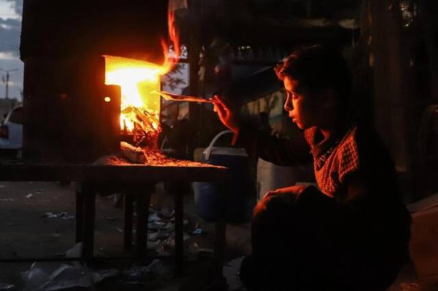 11月11日，一名男孩在加沙地带南部城市汗尤尼斯街头用柴火做饭。新华社发（里泽克·阿卜杜勒贾瓦德摄）