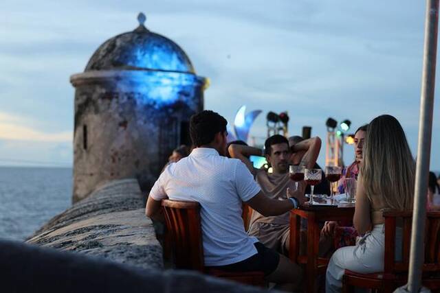 人们在卡塔赫纳古城墙上的酒吧聚会，欣赏加勒比海落日。唐薇摄
