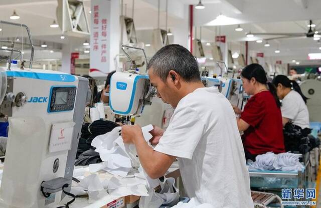 中乔体育股份有限公司的制鞋车间里，工人正在缝纫布料。新华网蒋巧玲摄