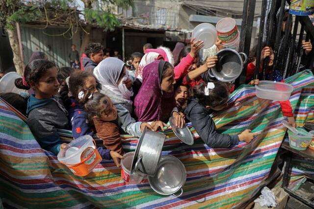 11月19日，在加沙地带南部城市拉法，人们领取救济食物。新华社发（里泽克·阿卜杜勒贾瓦德摄）