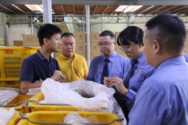 廖志略代表(左一)向茂名市检察院检察干警介绍化橘红成品的药用价值。