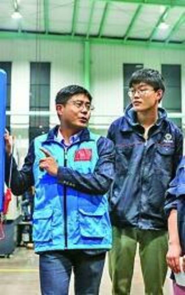 浙江湖州，教师（左一）在车间内开展夜校培训。周洪峰摄光明图片/视觉中国