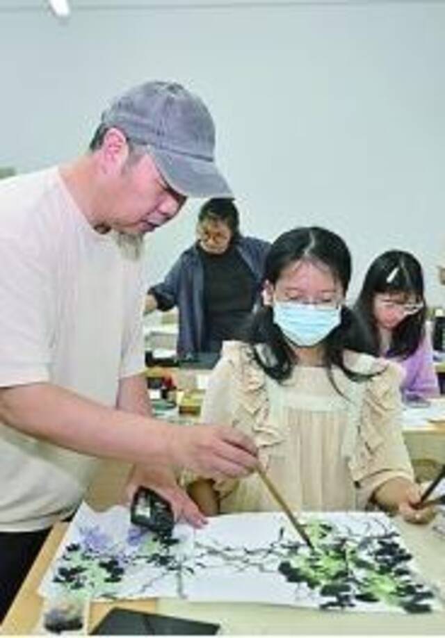 在上海市民艺术夜校秋季班上，老师（左一）在指导学员画国画。新华社发