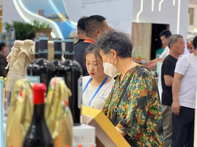 在第三十二届哈尔滨国际经济贸易洽谈会，参展商向顾客介绍商品（6月17日摄）。新华社记者刘赫垚摄