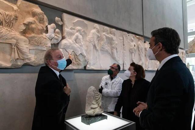 2022年1月10日，在希腊雅典卫城博物馆，希腊总理基里亚科斯·米佐塔基斯（右一）在观看一块原保存于意大利一家博物馆的雅典卫城帕特农神庙石雕碎片。新华社发（马里奥斯·罗洛斯摄）