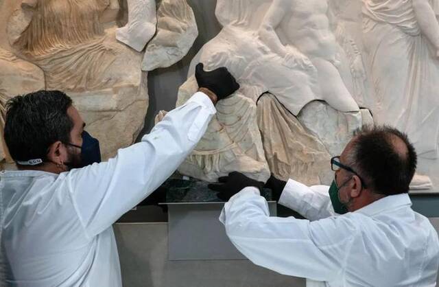 2022年1月10日，在希腊雅典卫城博物馆，工作人员正在将一块原保存于意大利一家博物馆的雅典卫城帕特农神庙石雕碎片放回原位。新华社发（马里奥斯·罗洛斯摄）