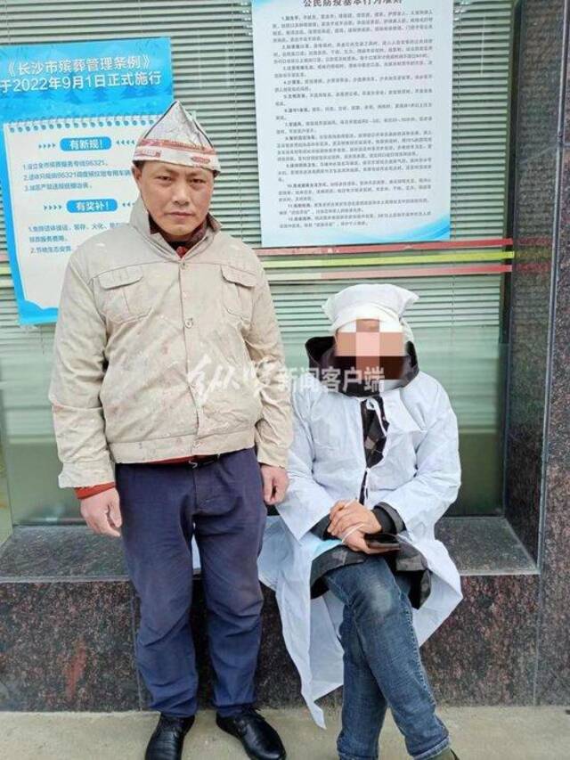 为了证明自己当天穿的不是“孝服”，周建湘（左一）专门与一位身穿孝服的人合影进行对比。（来源/受访者提供）