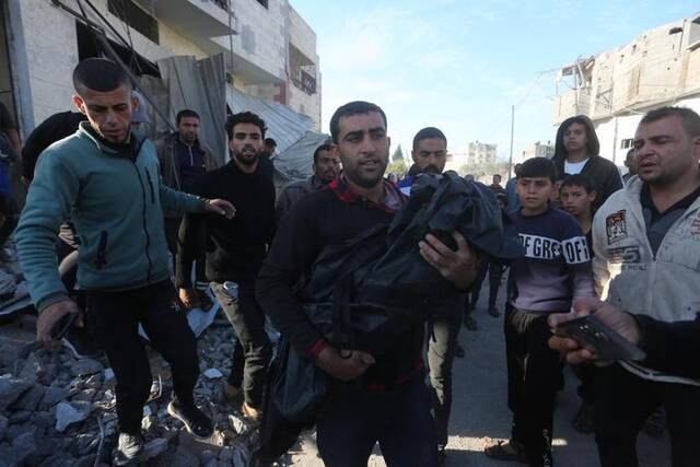 12月4日，在加沙地带南部城市拉法，一名男子抱着以军空袭遇难者的遗体。新华社发（哈立德·奥马尔摄）