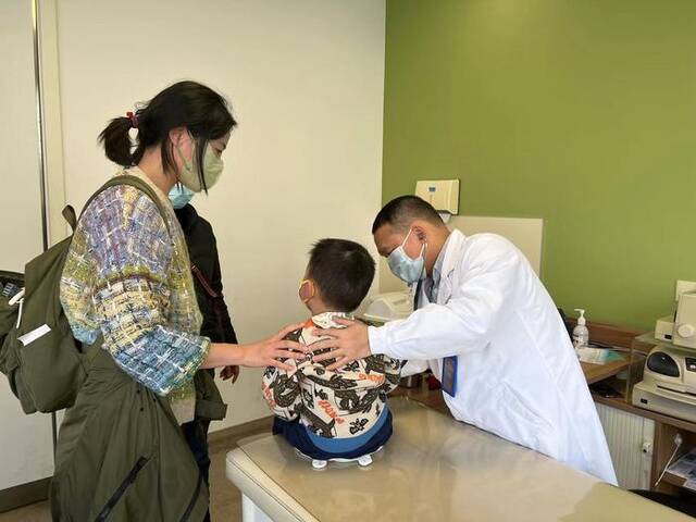丁国栋医生正在帮一名患儿做检查。