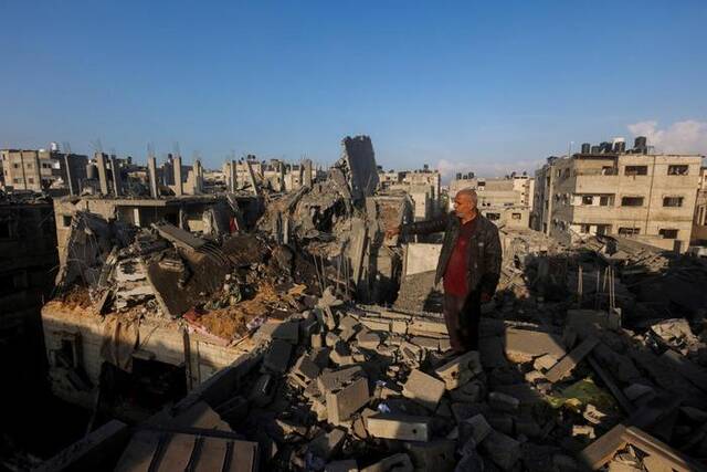 ▲12月6日，在汗尤尼斯，一名巴勒斯坦人查看遭以军空袭后的建筑废墟。图据新华社