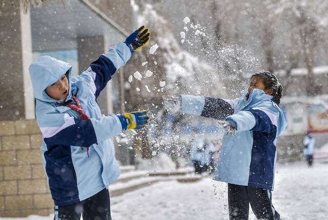 2023年12月12日，乌鲁木齐市第十一小学的学生们在课间休息时打雪仗。ICphoto图