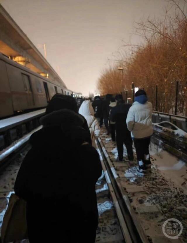 乘客踩着雪步行撤离现场。图片来源/网络