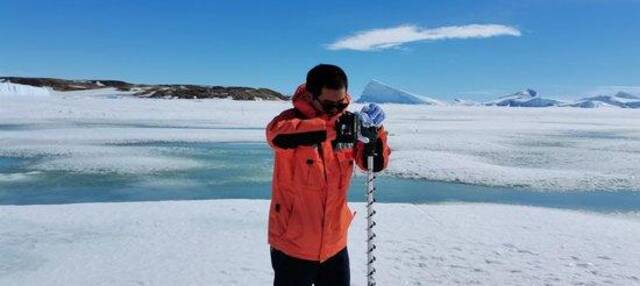 （▲中国第37次南极科学考察队队员麻源源正在进行冰面打孔，测量冰厚度）