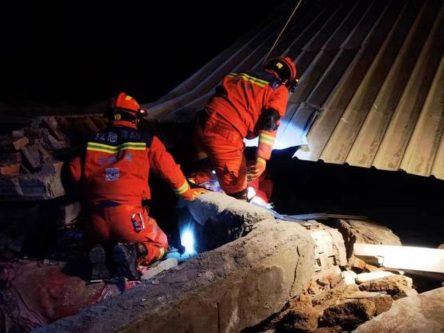 12月19日，甘肃临夏积石山县大河家镇康吊村二社，消防人员正在救援两名被困人员。图/新华社