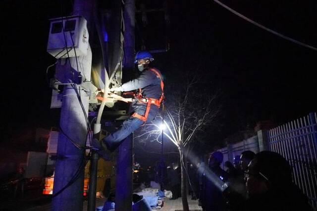 12月19日，在甘肃临夏州积石山县中西医结合医院门口，电力部门工作人员抢修电力设施。新华社记者马希平摄