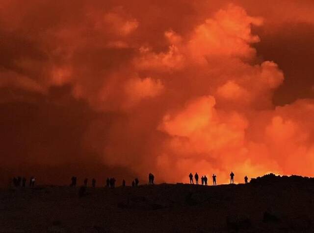 ▲一群人在喷发地点附近观看火山喷发