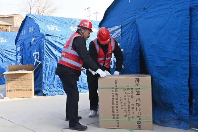12月19日，积石山县大河家镇大河村安置点，救援人员在搬运物资。范培珅摄/新华社
