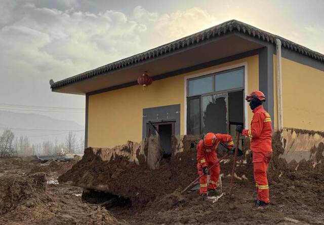 12月19日，在青海省海东市民和回族土族自治县中川乡金田村，救援队员正在清理受灾房屋旁的淤泥。新华社记者李宁摄