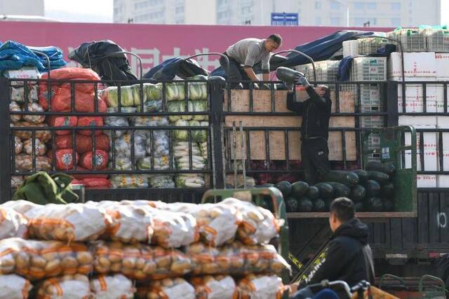 12月20日，工作人员在南京农副产品物流中心蔬菜批发区装卸蔬菜。新华社记者李博摄