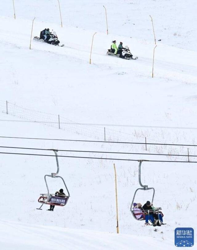 ↑12月21日，游客在那拉提国际滑雪场体验雪上摩托（上）和索道缆车项目。