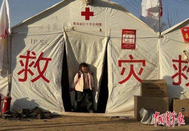 12月25日下午，在金田村安置点，一个小女孩背着书包站在帐篷前。中青报·中青网见习记者赵丽梅/摄