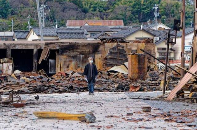 1月4日，一名市民查看日本石川县轮岛市“轮岛早市”废墟。图源：新华社