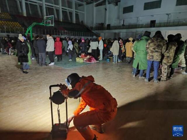 1月23日凌晨，国网阿合奇县供电公司工作人员在阿合奇县体育馆临时安置点架设照明设备。新华社发（满肃儿摄）