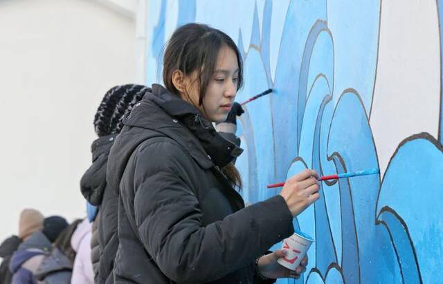 青年志愿者不顾天气寒冷，创意手绘墙画，扮靓村庄环境，助力乡村振兴。通讯员周强摄