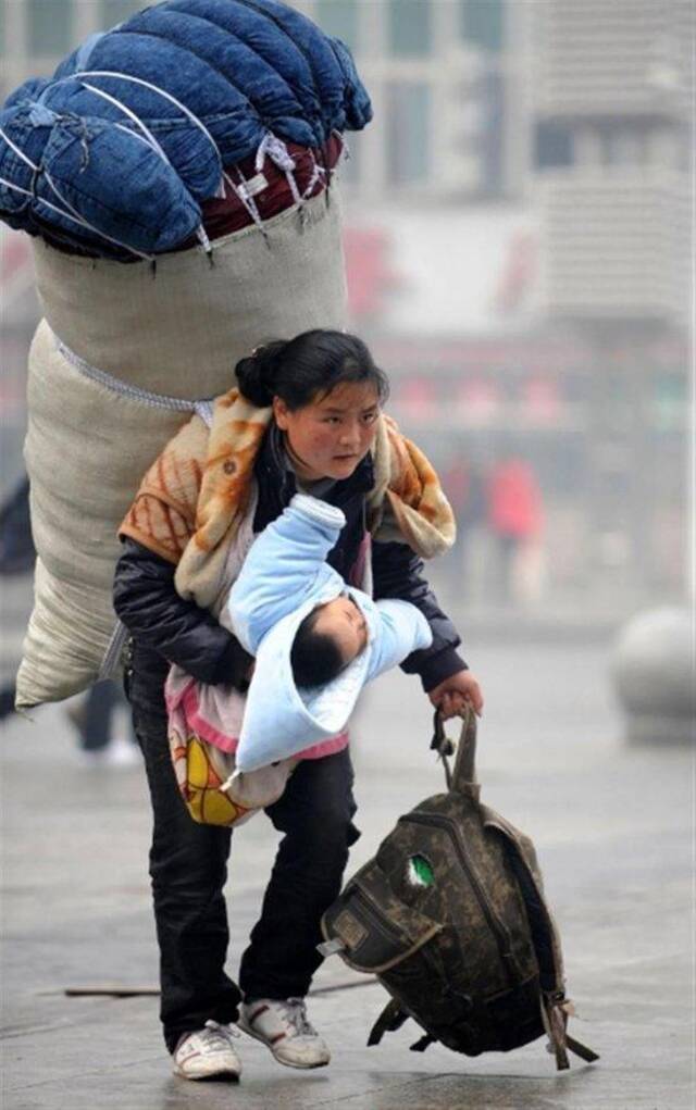 2010年1月30日，巴木玉布木背着大包、抱着孩子在南昌火车站匆忙赶车（图片来源：新华社）
