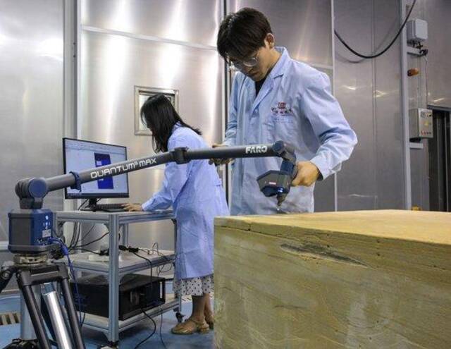 在敦煌研究院多场耦合实验室中，工作人员正在对庆阳北石窟寺砂岩样品进行三维扫描分析（2023年8月3日摄）。新华社记者李贺摄