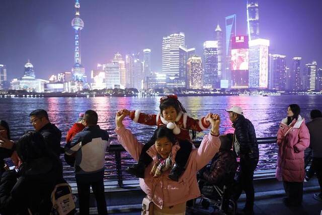 2024年2月9日，上海，游客带着孩子在外滩滨江步道上欣赏黄浦江两岸美景。中新社记者殷立勤图
