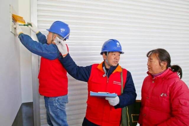 国网安徽合肥供电公司工作人员为居民王登月检查家中用电线路。