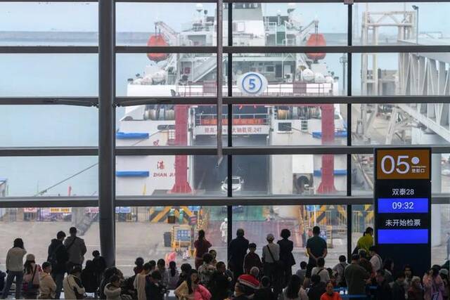 △2月16日，海口新海客运综合枢纽候船大厅，准备排队登船的游客隔窗望向码头轮渡。