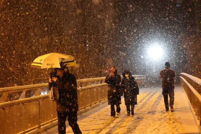2月20日，北京市东直门南大街过街天桥，市民在雪中行走。新京报记者王贵彬 摄