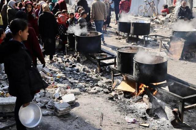 2月27日，在加沙地带北部的杰巴利耶难民营，人们等待领取食物。新华社发（穆罕默德·阿里摄）