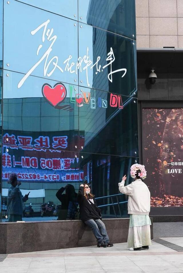 两位游客在已闭店的胖东来时代广场店门口拍照（3月6日摄）。