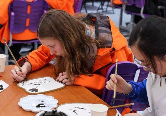 3月18日，在清华大学附属中学，美国华盛顿州中学生代表团的成员与中国中学生一起体验水墨画扇面绘制。新华社记者殷刚摄