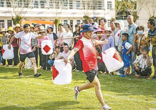 近日，海南省琼海市石壁镇的农民在进行挑担子赛跑趣味运动比赛。图片来源：视觉中国