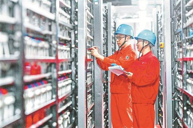 国家电网浙江省湖州市长兴县供电公司的工作人员正在蓄电池室检测并网后单个蓄电池的电压。图片来源：视觉中国