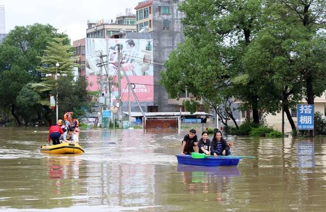 4月21日，广东清远英德市浛洸镇居民在积水的道路上乘船出行。新华社记者黄国保摄