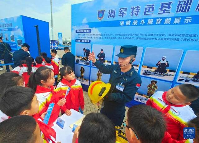 海军唐山舰靠泊河北省唐山市开放展示，官兵为小学生演示消防战斗服穿戴（4月20日摄）。新华社发（马玉彬摄）