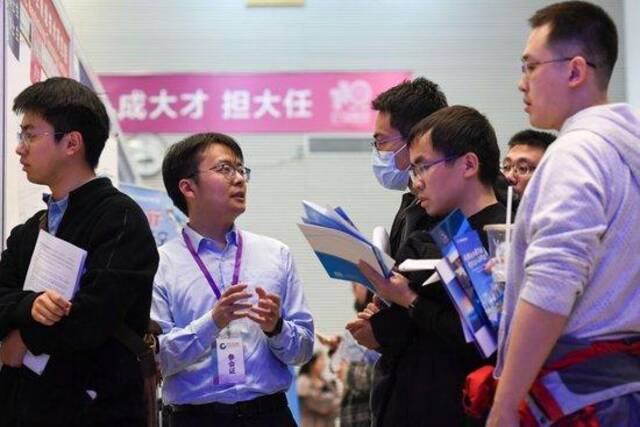 在清华大学举办的2024届毕业生大型就业洽谈会上，一名用人单位招聘人员（左二）与求职毕业生交流（2024年3月15日摄）。新华社记者鞠焕宗摄