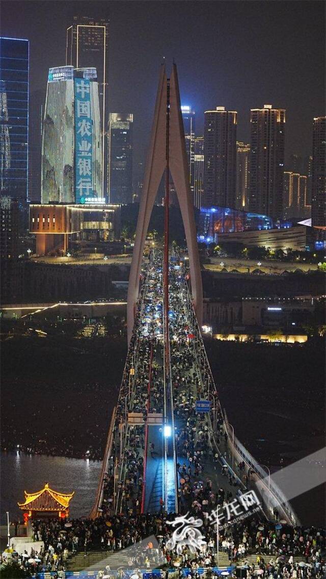 游客冒雨登上千厮门嘉陵江大桥。