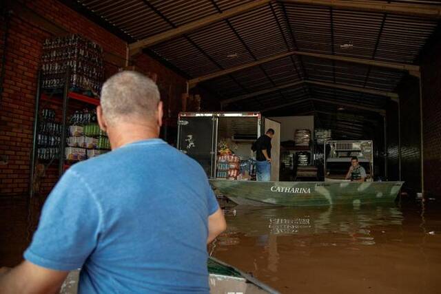 5月9日，在巴西南里奥格兰德州圣莱奥波尔多，人们在洪水中搬运货物。新华社发(克劳迪娅·马尔提尼摄)
